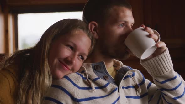 Caucasian couple spending time at home together, looking at the window, drinking beverage