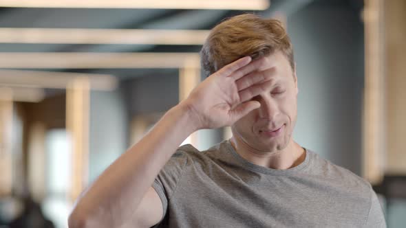 Tired Fitness Man Wiping the Sweat at Gym. Sportsman Standing in Fitness Center alt