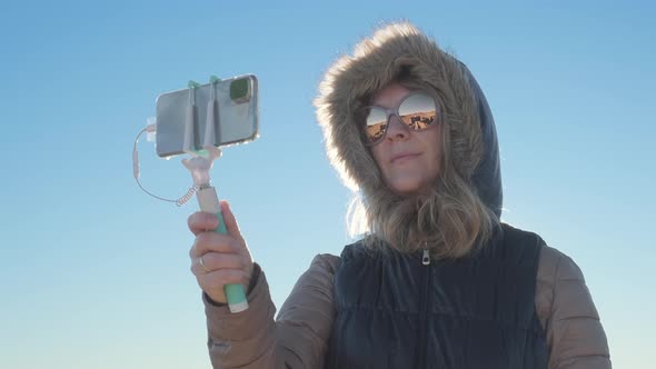 Closeup of a Pretty Woman Taking Selfies in Cold and Windy Weather and Sharing Via Social Media