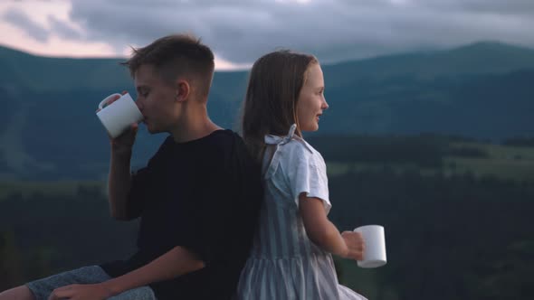 Siblings Enjoying Hot Drink in Mountains