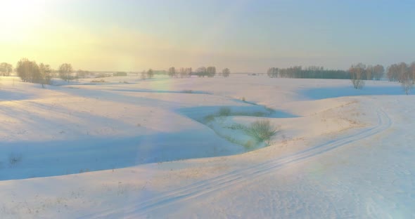 Aerial View of Cold Arctic Field Landscape Trees with Frost Snow Ice River and Sun Rays Over Horizon