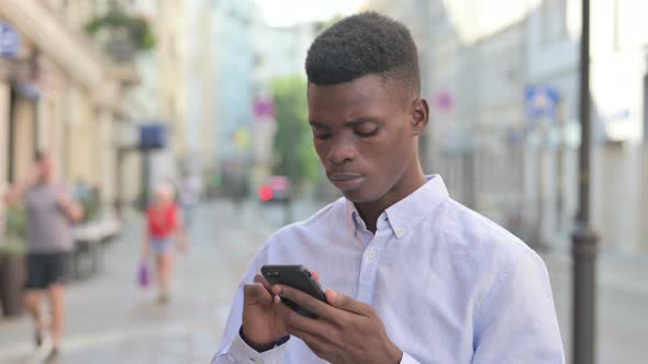 African Man Using Smartphone While Standing Outdoor