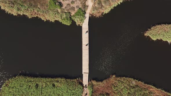 Aerial View of Unrecognisable People Walking Along a Wood Bridge