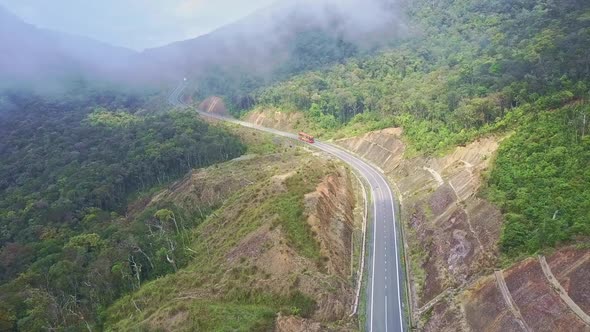 Aerial View Red Bus Drives Along Empty Highway on Mountain