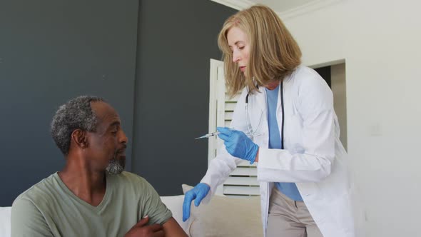 Caucasian senior female doctor giving vaccination to african american senior male patient