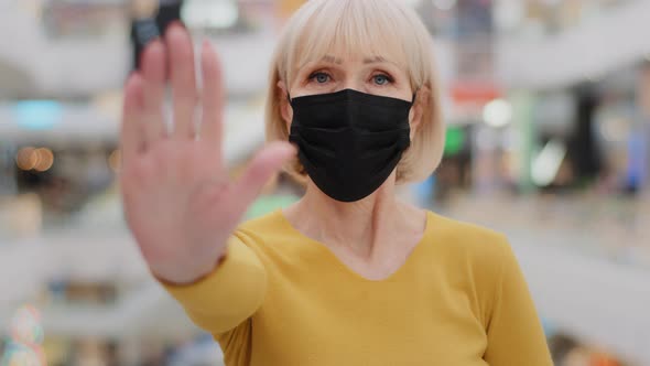 Serious Middleaged Caucasian Woman in Medical Mask Protects Health Holding Hand in Front Put Palm