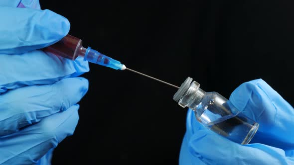 Doctor's Hand Holds Syringe Red Vaccine Bottle Hospital Black Background