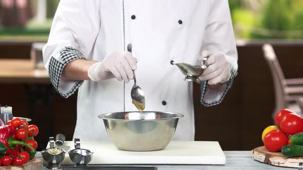 Chef with Spoon Adding Sauce.