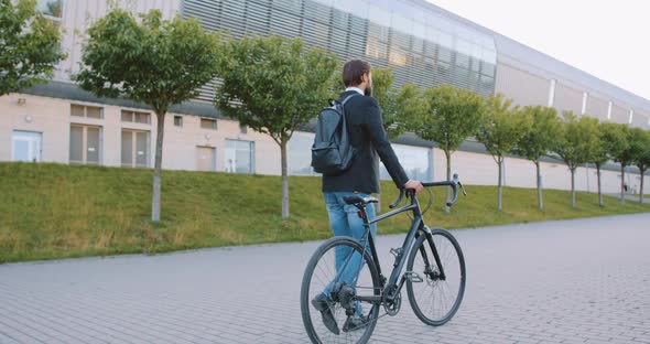 Man in Jacket and Jeans Which Walking with His Bike on Cobbled Street