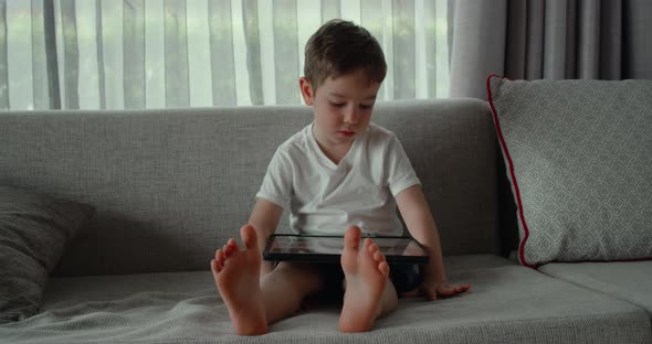 Curious Cute Preschool Kid Boy Using Digital Tablet Technology Device Lying on Carpet Floor Alone