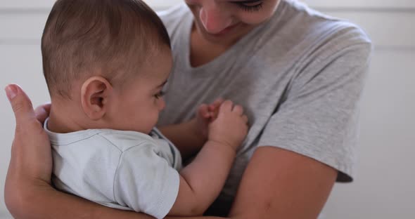 Young loving mother embracing her baby at home