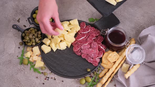 Making Meat and Cheese Antipasto Plater Woman Putting Pieces of Parmesan Hard Cheese on Stone
