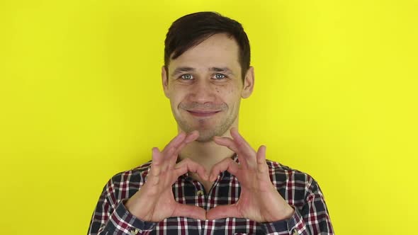 Funny, Pretty Guy Smiling and Folding a Heart Sign Out of His Hands. Portrait of a Young Guy, He