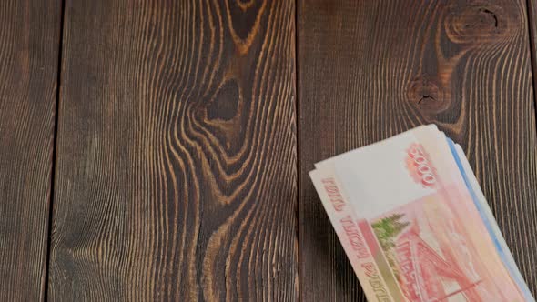 Stack of Russian Rubles Banknotes Dropping on Wooden Surface and Sliding