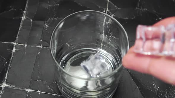 Falling ice cubes and ice tea pouring into a glass 