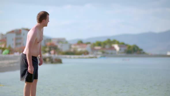 Young Man Tourist Walking on Sea Shore in Summer