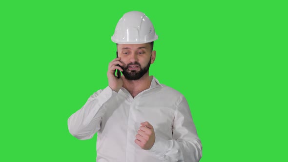 Engineer in White Shirt and Hard Hat Talking on His Mobile Phone on a Green Screen, Chroma Key.