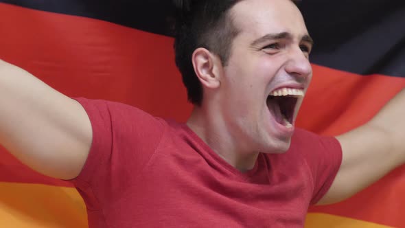 German Young Man Celebrating while Holding the Flag of Germany