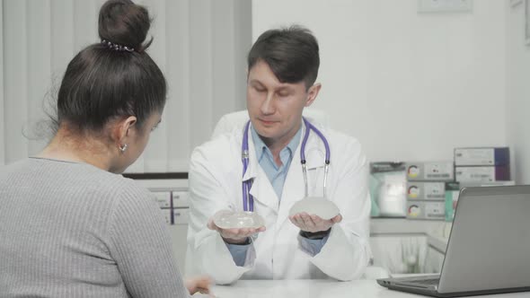 Plastic Surgeon Showing Types of Silicone Breast Implants to the Patient