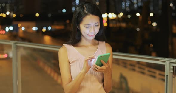 Woman use of smart phone in the street at night 