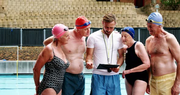 Swim coach training seniors on digital tablet