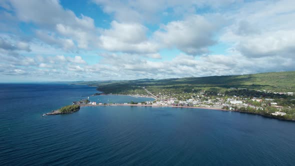 High altitude drone view of cloud shadowsing over trees on a shoreline