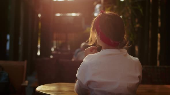 Happy Girl in a Cafe Calling Someone By Raising Her Hand Summer Time Enjoyment and Lifestyle