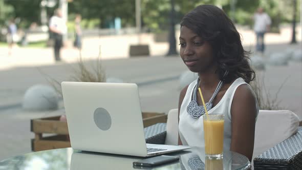 Young African Woman Sitting Alone in a Cafe Having a Videoconferance on a Laptop