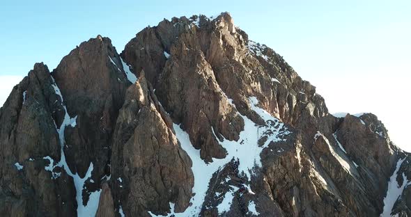 The Rocky Peak Is Covered with Snow. There Is a Queue of People on The Rise. Drone Footage