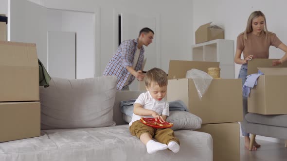 Young Couple with Kid at Home Unpacking Boxes After Relocating