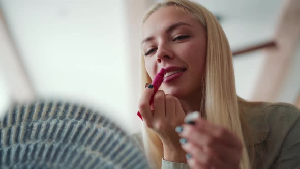 Smiling blond woman paint lips with balm