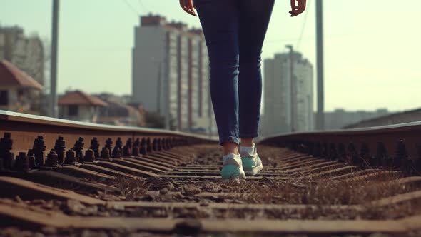 Tourist Legs Walking On Railway Middle Of Rail. Lonely Woman Feet In Jeans Walking On Rail Road.