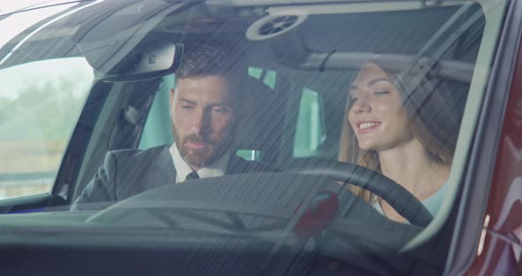 Dealer Helping Woman to Choose Car at Salon