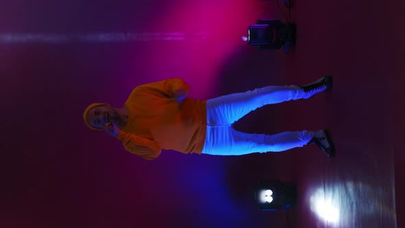 Vertical Video. Incendiary Funny Singer in Yellow Clothes Dancing and Singing with a Microphone in