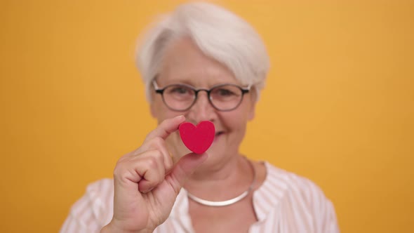 Happy Senior Woman Showing the Heart Shape Between Her Fingers. Emotion Love and Support Concept