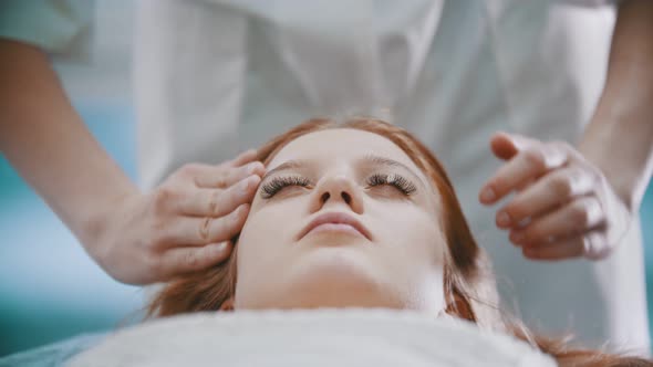 Massage - a Masseuse Is Kneading Her Young Clients Forehead