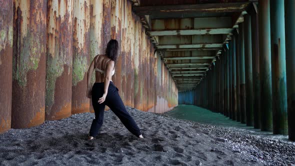 a Barefoot Woman Dances Under the Pillars of the Bridge