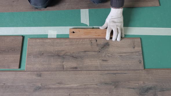 A Worker Hands Knocking on a Laminate Connecting the Panels with a Lock Click