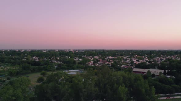 Aerial flight over urban area with parks, houses and trees.