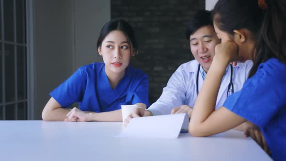 Group of Young Asian Doctor and Nurse Sitting During Break Discussing Serious Patient Case