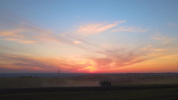 Tractor Spraying Fertilizers with Insecticide Herbicide Chemicals on Agricultural Field at Sunset