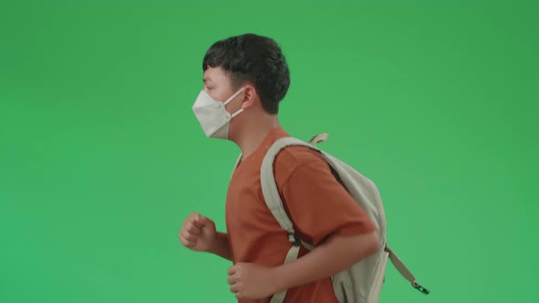 Side View Of Asian Boy Student Wearing A Mask, Running To School On Green Screen Chroma Key