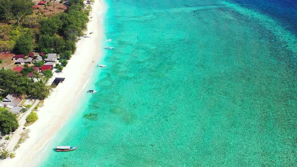 Beautiful beach coastline with shallow aqua waters and small boats docked at the shore