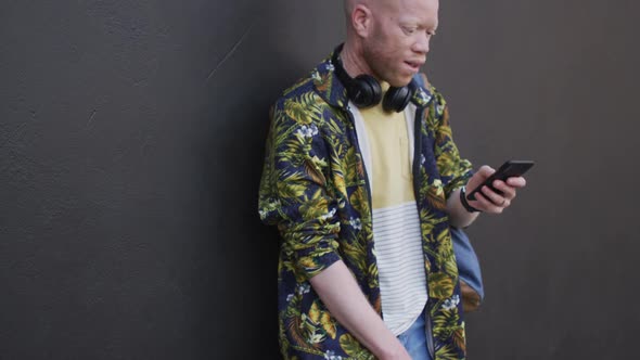 Thoughtful albino african american man with dreadlocks using smartphone