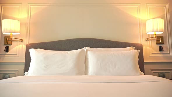 Tilt down shot of a modern freshly made resort hotel double bed with white blankets and bedsheets an