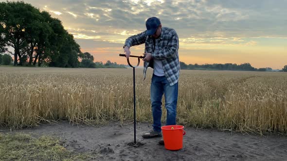 Agronomist Taking Sample with Soil Probe Sampler Grain Field at Dawn