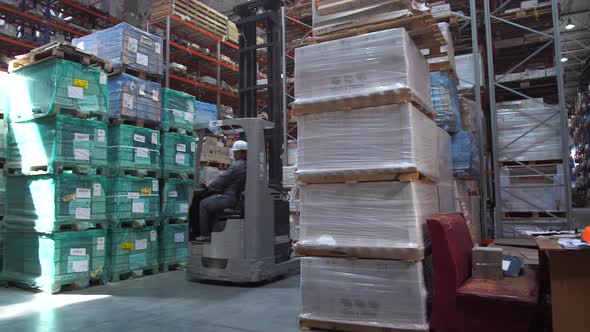 Travel Worker on a Forklift Through the Logistics Warehouse