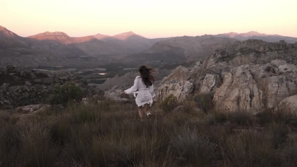 Woman running in a rocky semi arid mountain with shrubs around her, freedom and joy concept in the w