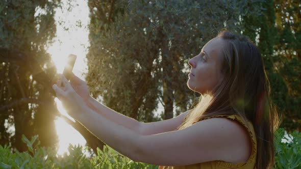 Young Woman in a yellow t-shirt making selfie by the phone against the background