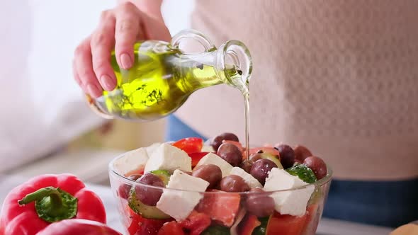 Greek Salad Preparation Series Concept  Woman Pouring Olive Oil Into Bowl with Chopped Vegetables